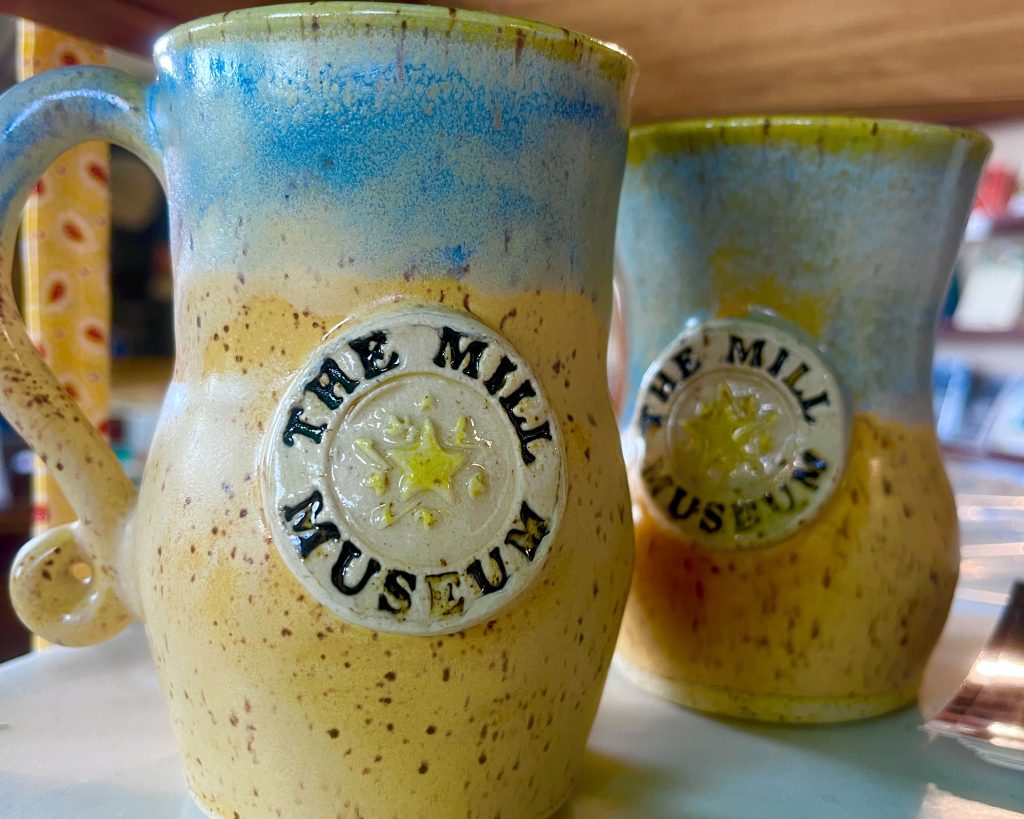 Mugs from a local pottery bearing the Mill Museum's logo in the gift shop.