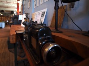 An atmospheric close-up view of a Merrow overlock sewing machine in the Windham Textile and History Museum's Dugan Hall industrial exhibit.
